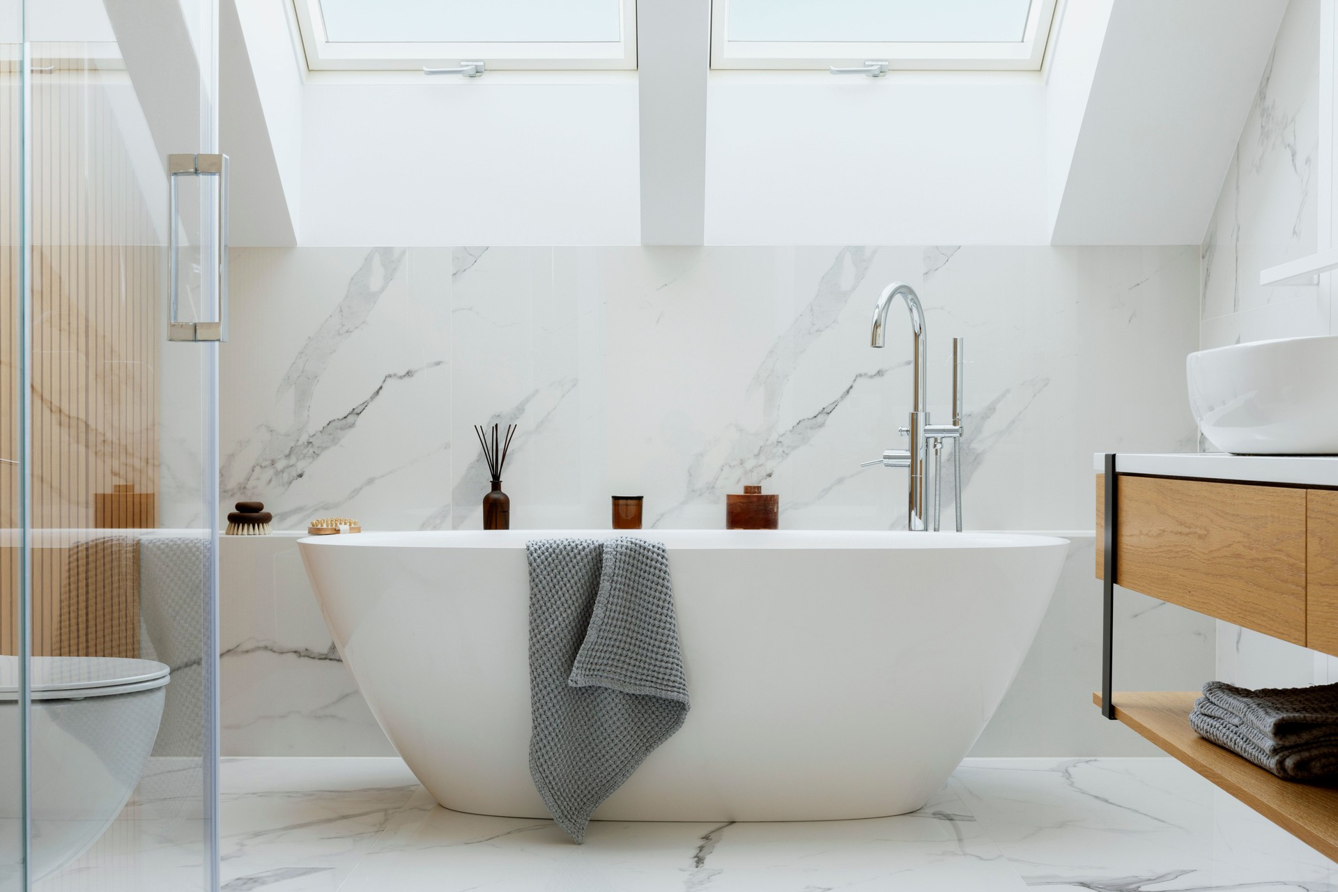 Stylish bathroom interior design with marble panels. Bathtub, towels and other personal bathroom accessories. Modern glamour interior concept. Roof window. Template."n