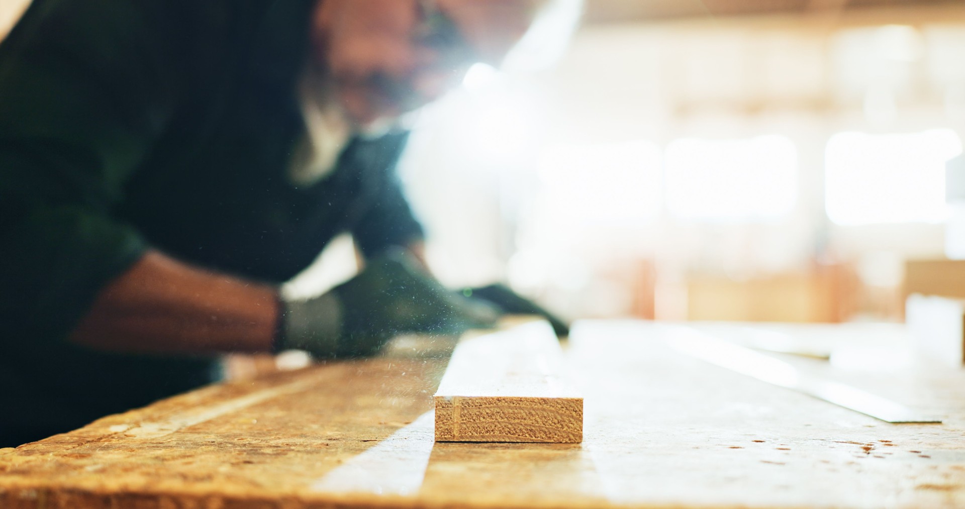 Carpenter, woodworking and man with sandpaper, polishing and smooth surface with tool and manufacturing. Production, artisan and person with gloves for safety, grip and shape of material in business